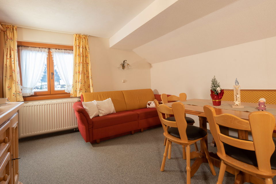 Wohnbereich der Ferienwohnung Bärenkopf mit rotem Sofa