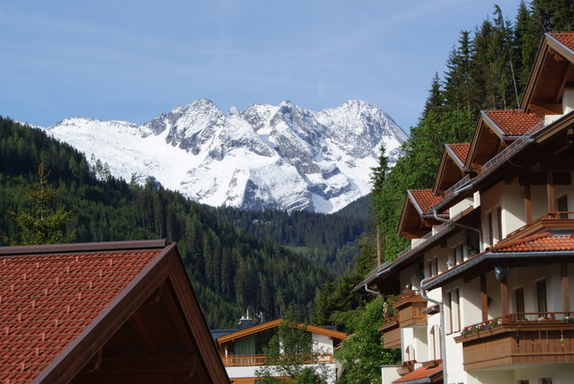 Häuser in Gerlos-Ried vor grünen Hängen und schneebedeckten Berggipfeln