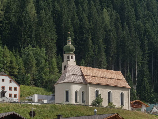 Pfarrkirche von See im Paznaun vor bewaldetem Berghang