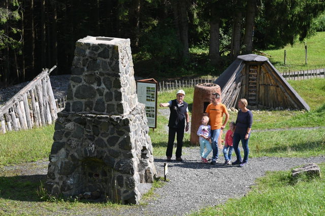 Familie mit Kindern auf dem Freigelände der Erzgruben Burgberg zwischen Kohlemeiler und Hochofen.