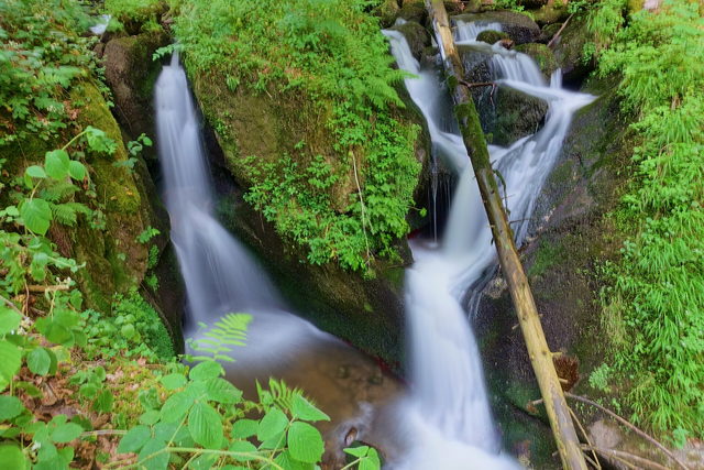 Kaskaden des Kleinen Höllbachwasserfalls zwischen Felsen und Wald.
