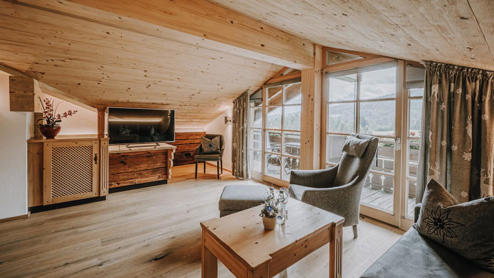 Wohnbereich mit Dachbalken und Fensterfront in der Suite Obheiter.