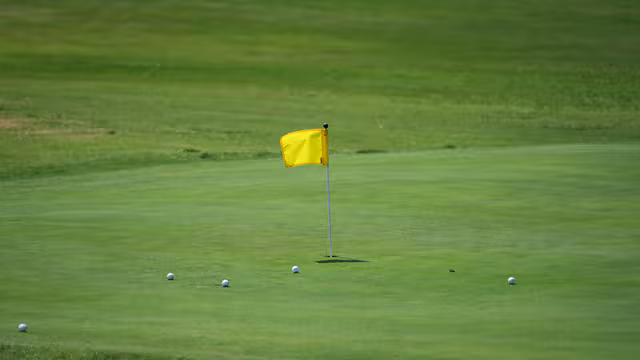 Symbolbild: Golfgreen mit Fahne und Golfbällen. Keine Originalaufnahme des Anbieters.