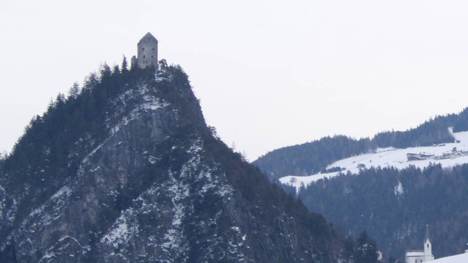 Ruine Kronburg auf einem bewaldeten Felsen bei Zams im Winter