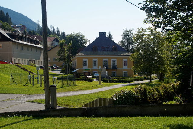 Historischer Marktplatzbereich von Bad Bleiberg mit Gebäude, Grünflächen und Bergbauerinnerungen