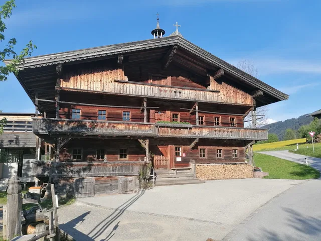 Traditionelles mehrstöckiges Holz-Chalet mit Balkonen in ländlicher Umgebung.