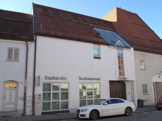 Historisches Archiv- und Museumsgebäude mit weißer Fassade, rotem Dach und Pkw davor