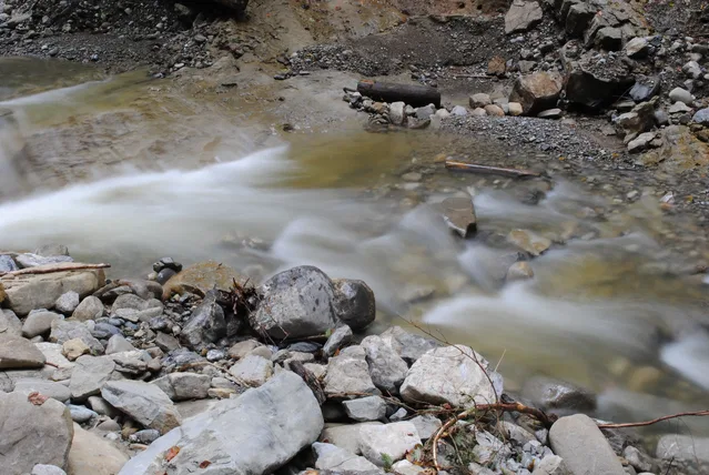 Verwaschen fließendes Wasser in einem felsigen Bachbett mit Steinen.
