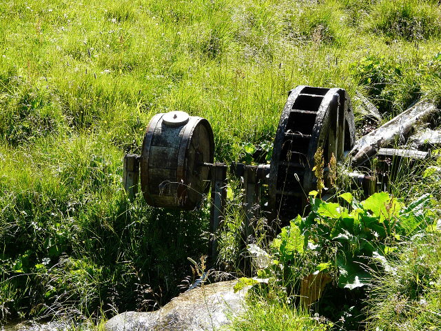 Symbolbild: hölzernes Butterfass mit Wasserantrieb als Motiv für historische Almwirtschaft