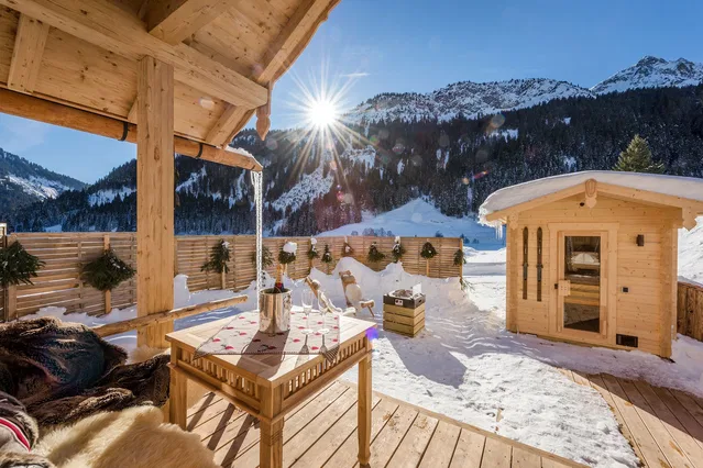 Verschneite Terrasse mit Saunahäuschen und Bergblick