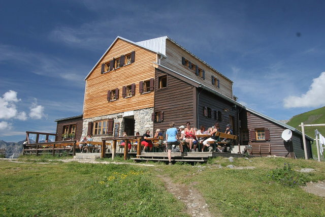 Stuttgarter Hütte mit Terrasse und Wanderweg auf einer Bergwiese