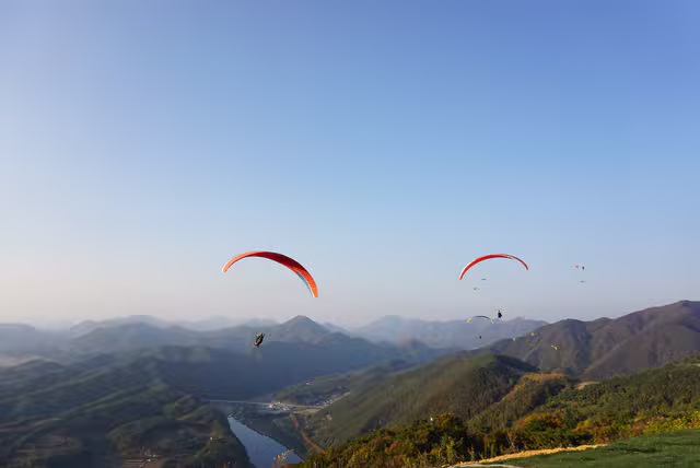 Symbolbild: Gleitschirmflug über einer Berglandschaft. Keine Originalaufnahme des Anbieters oder Fluggebiets.