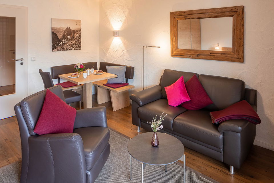 Wohnbereich der Ferienwohnung Höfats mit Ledersofa, Sessel und Essecke.