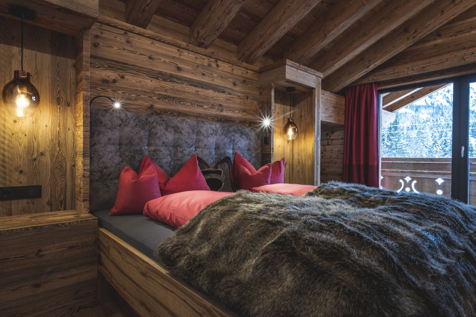 Schlafzimmer mit Doppelbett, Holzwänden und roten Kissen