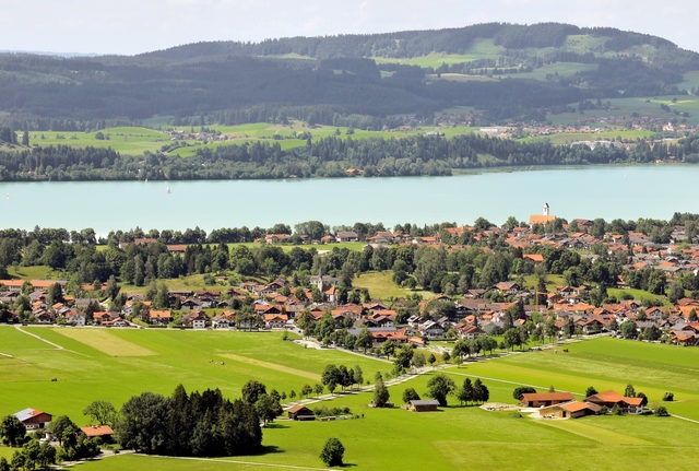Landschaftliches Dorf am Seeufer mit Feldern und Hügeln