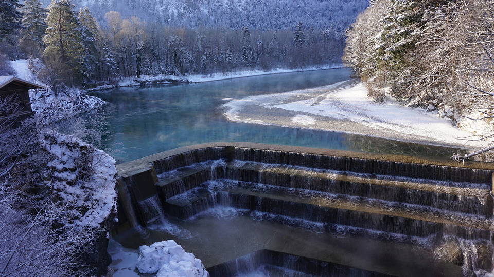 Verschneite Stufen des Lechfalls vor dem ruhigen Fluss