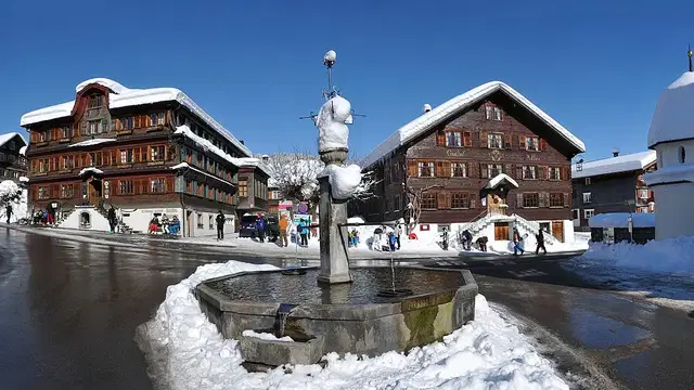 Dorfzentrum von Schwarzenberg im Winter mit Dorfbrunnen. Ortsmotiv zur Ausflugsplanung.