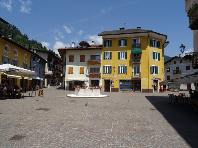 Historischer Platz in Fiera di Primiero mit Brunnen und farbigen Häuserfassaden