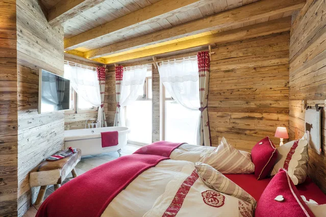 Schlafzimmer mit Doppelbett und freistehender Badewanne