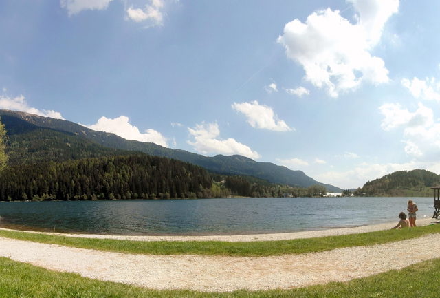 Uferweg am Serraia-See mit Wiese und bewaldeten Höhen
