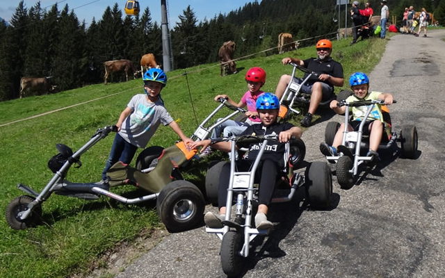Mountaincart-Gruppe auf der Bergstraße mit Helmen und Blick ins Allgäu