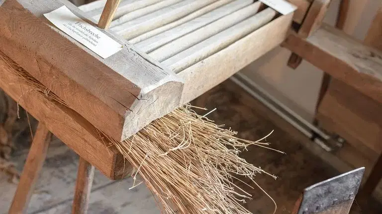 Historischer Flachsverarbeitungsapparat aus Holz mit Flachsfasersträngen