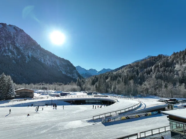 Winterliches Skating-Areal in Berglandschaft bei Sonnenschein, schneebedeckte Bäume und Berge.