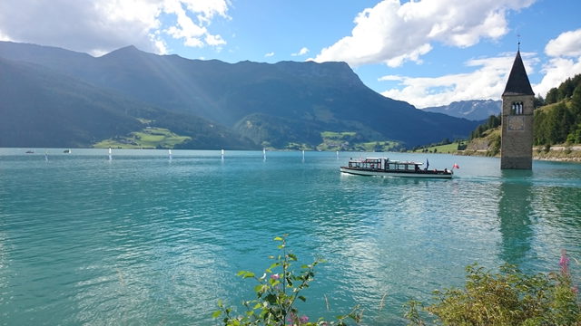 Kirchturm von Altgraun im Reschensee mit einem Ausflugsschiff, Aufnahme 2016