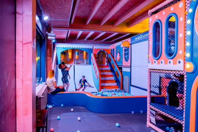 Bunt beleuchteter Indoor-Spielplatz mit Bällebad, Treppe und Kletterelementen