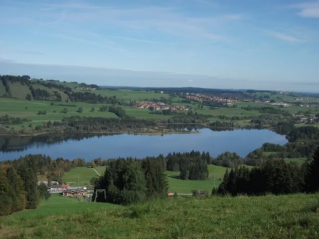 Landschaft mit See, Felder, Wald und Dorf am Ufer