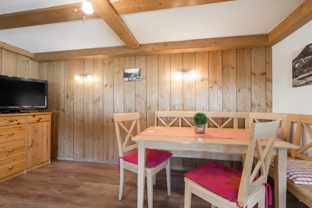 Rustikaler Essbereich mit Holzwand, Deckenbalken und Esstisch mit Stühlen