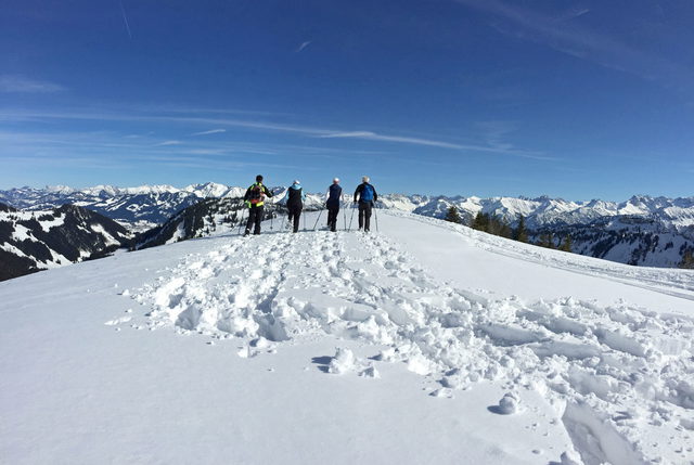 Schneeschuhgruppe auf dem breiten verschneiten Gipfelrücken