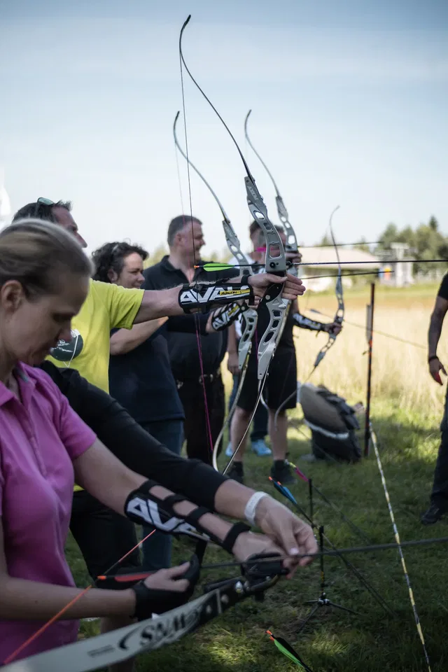 Gruppe beim Bogenschießen auf einer Wiese