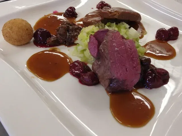 Rosa gebratenes Fleisch mit Sauce, Gemüse und Beilagen auf weißem Teller