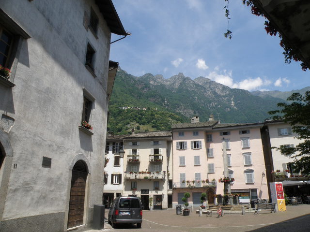Piazza Rodolfo Pestalozzi mit Brunnen, historischen Häusern und Bergen in Chiavenna
