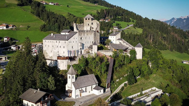 Burg Heinfels auf ihrem Hügel zwischen Wiesen und Bergen