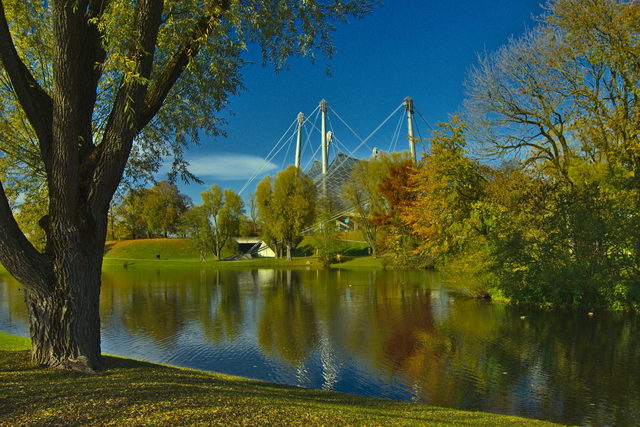 Olympiasee mit Bäumen und Zeltdach des Olympiastadions in München