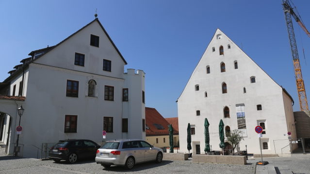 Aventinusplatz in Abensberg mit Freihaus links und Herzogskasten rechts, Autos im Vordergrund und Baukran rechts auf der Aufnahme von 2019
