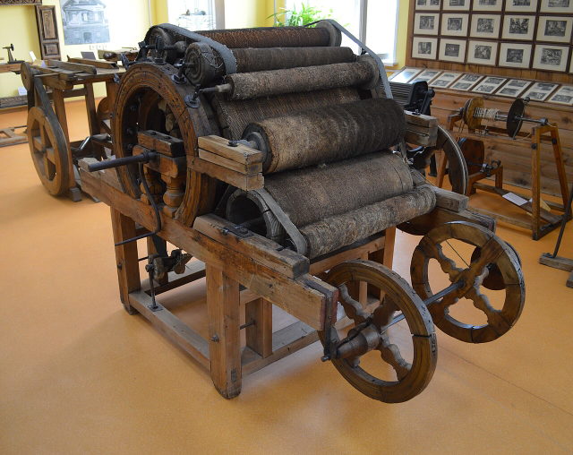 Symbolbild: historische Wollkardiermaschine mit Holzrahmen und Walzen