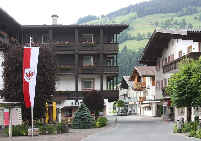 Dorfplatz in Westendorf mit traditionellen Häusern und Tiroler Fahne