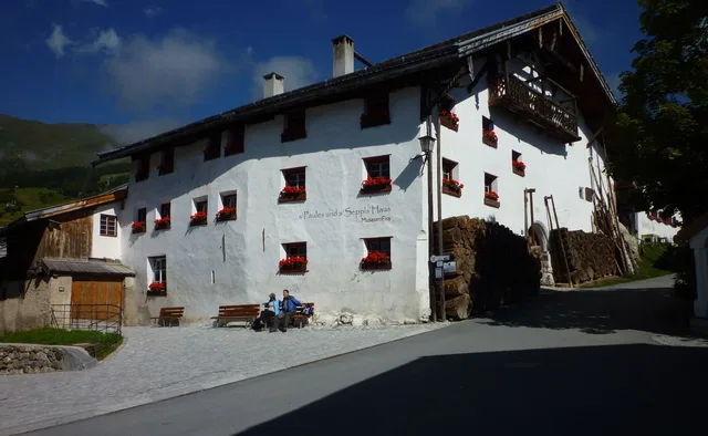 Alpenhaus mit roten Blumenfenstern an der Straßenseite