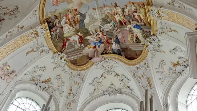 Barockes Deckenfresko mit weißem und goldenem Stuck über Orgelpfeifen in der Basilika Ottobeuren. Ortsmotiv.