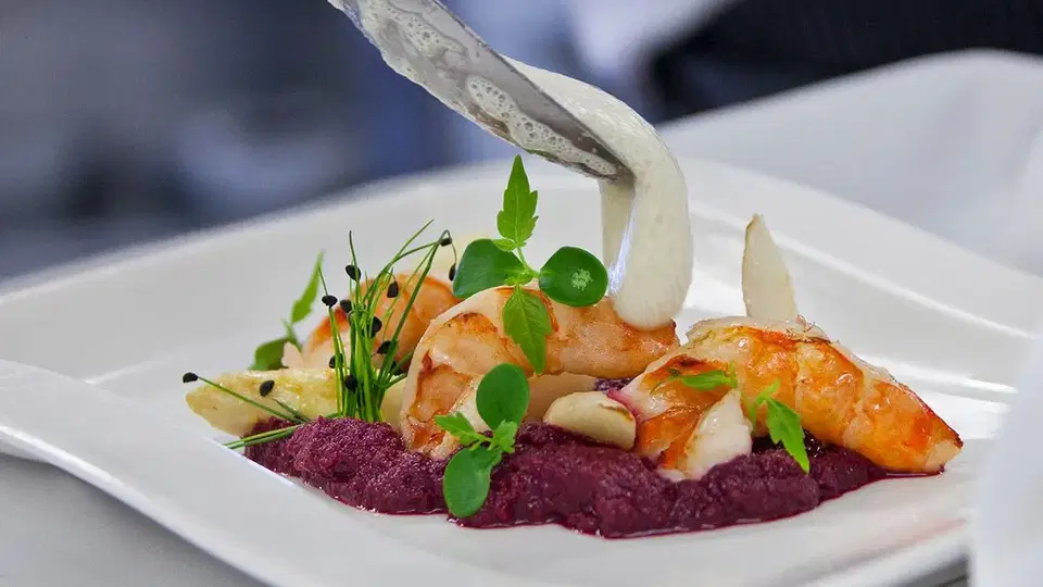 Garnelen mit Gemüse und heller Sauce auf einem Teller