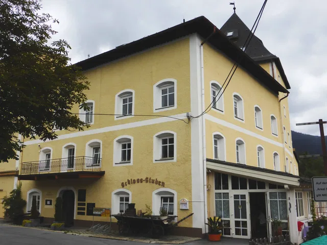 Gelbes Gebäude mit Ladenfront und Balkon auf der linken Seite