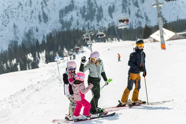 Familie beim Skifahren auf einer schneebedeckten Piste in Oberstdorf