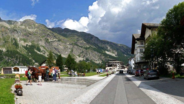 Via da Marias in Sils Maria mit Häusern, Pferdekutschen und Bergkulisse