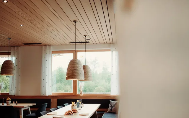 Heller Gastraum der Gaststube Bienenkorb mit Holzdecke und gedeckten Tischen
