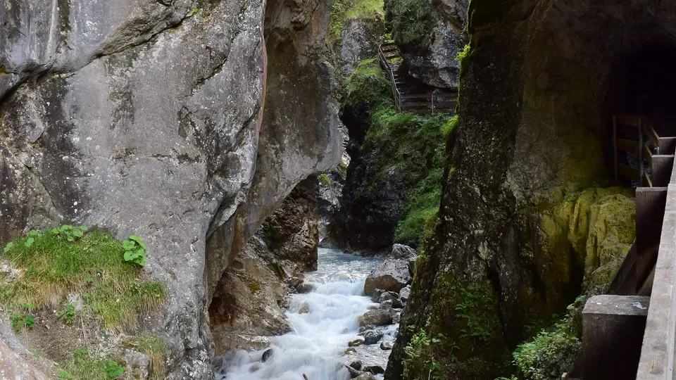 Enge Felsenschlucht mit reißendem Fluss und Holzweg am rechten Rand.
