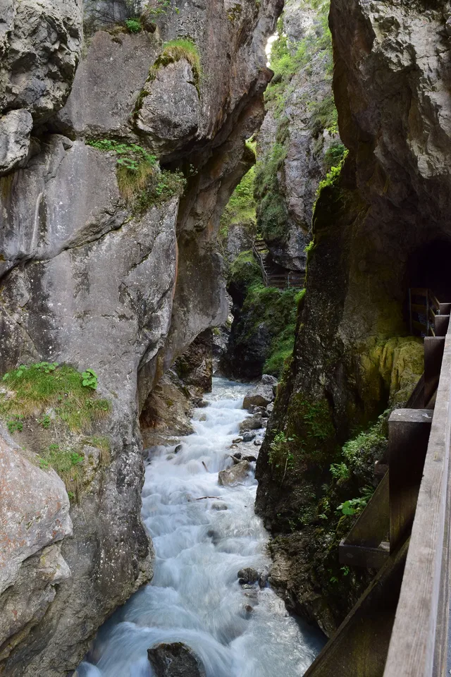 Enge Felsenschlucht mit reißendem Fluss und Holzweg am rechten Rand.