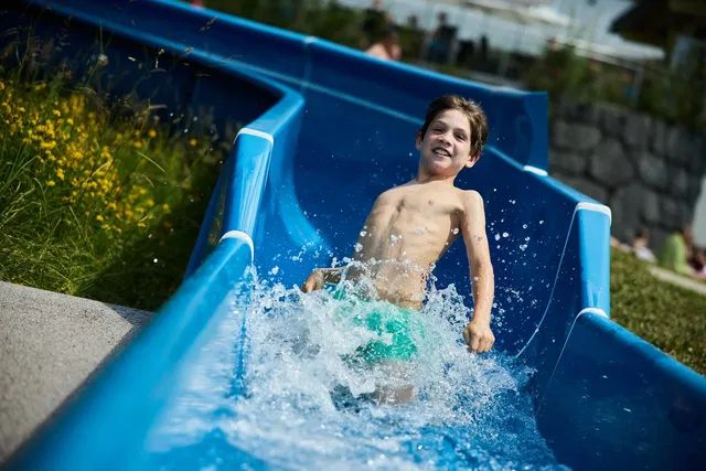 Kind auf einer Wasserrutsche im Freibad Riezlern